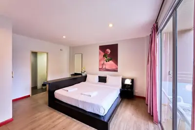 a bedroom with a bed and a large window at Jinta Andaman in Kata Beach