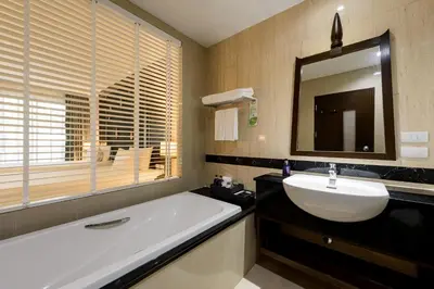 a bathroom with a tub and a sink and a mirror at Centara Anda Dhevi Resort & Spa Krabi in Ao Nang Beach