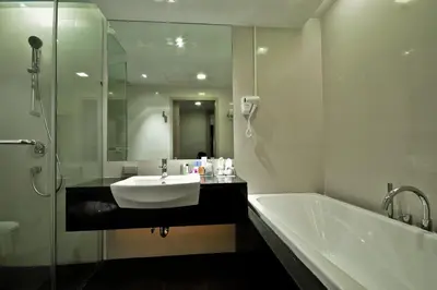 a bathroom with a sink and a tub and a mirror at ASHLEE Heights Hotel Patong in Patong Beach