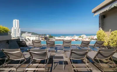 a group of chairs sitting on a balcony with the ocean at Gu Hotel Patong in Patong Beach