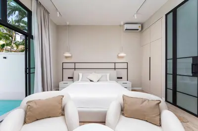 a bedroom with a white bed and two chairs at VILLA MIOS Private Pool 3 min Nai Harn Beach in Nai Harn Beach