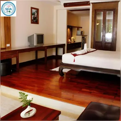 a bedroom with a bed and a desk with a television at Baan Pron Phateep in Patong Beach