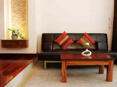a black leather couch with red pillows on a table at Baan Pron Phateep in Patong Beach
