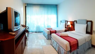 a hotel room with two beds and a television at Baan Pron Phateep in Patong Beach