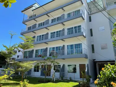 an apartment building with balconies and trees at Kasemsuk Hotel Karon in Karon Beach