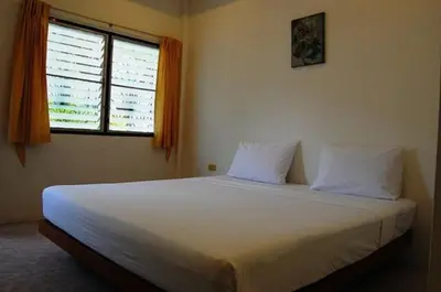 a bedroom with a bed with two pillows and a window at Hacienda Phuket, Patong in Patong Beach
