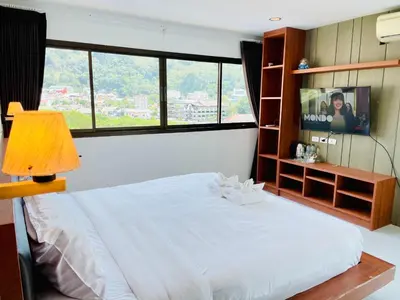 a bedroom with a white bed and a television at Good Nice Hotel in Patong Beach