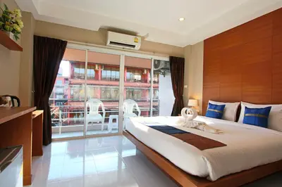 a bedroom with a large bed and a large window at Good Nice Hotel in Patong Beach
