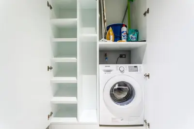 a laundry room with a washing machine and shelves at Emerald Terrace Patong in Patong Beach