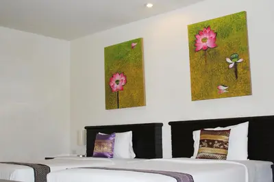 two beds in a room with two paintings on the wall at Lub Sbuy Hostel in Phuket Town