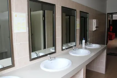 three sinks in a public bathroom with mirrors at Lub Sbuy Hostel in Phuket Town