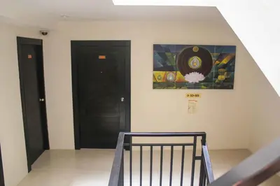 a staircase with two black doors and a painting on the wall at Lub Sbuy Hostel in Phuket Town