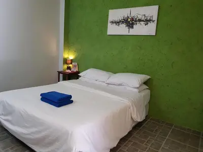 a bedroom with a white bed with a green wall at 2 Home in Chalong