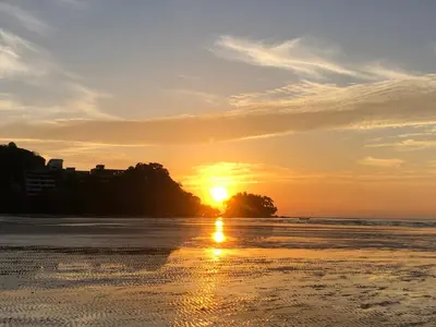 a sunset on a beach with the sun setting at Dang Sea Beach Resort - SHA in Nai Yang Beach