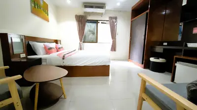 a bedroom with two beds and a table and a chair at Lucky Buako Hotel Patong in Patong Beach