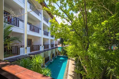 an apartment building with a swimming pool and trees at Phuket Meet Holiday Hotel-Rawai \u666e\u5409\u5c9b\u76f8\u9047\u82b1\u56ed\u5ea6\u5047\u9152\u5e97-\u62c9\u5a01\u5e97 in Rawai Beach