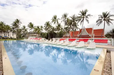 a pool at the resort with lounge chairs and palm trees at Angsana Laguna Phuket in Bang Tao Beach