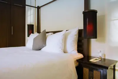 a bedroom with a bed with white pillows and a table at Two Bedroom Oriental Villa Nai Harn in Nai Harn Beach