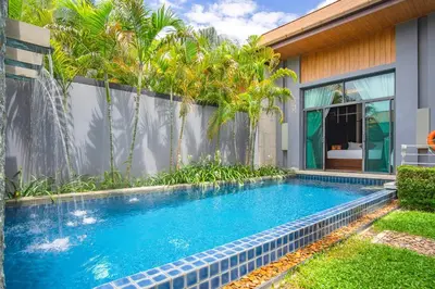 a swimming pool in front of a house with palm trees at ONYX Villa Naiharn - 1 Bedroom with private pool in Nai Harn Beach