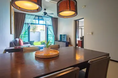 a dining room with a large wooden table with a plant on it at ONYX Villa Naiharn - 2 Bedrooms with private pool in Nai Harn Beach