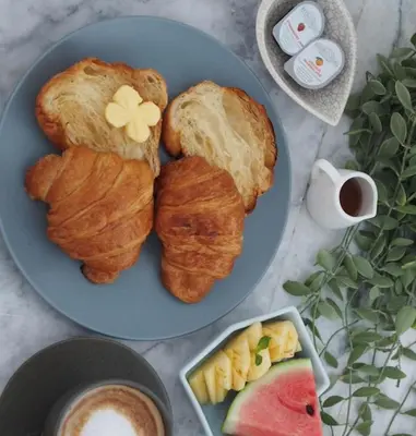 a blue plate with three croissants and a cup of coffee at ONYX Villa Naiharn - 3 Bedrooms with private pool in Nai Harn Beach