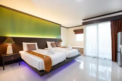 a bedroom with two beds and a green wall at Orchid Garden Hotel Patong in Patong Beach