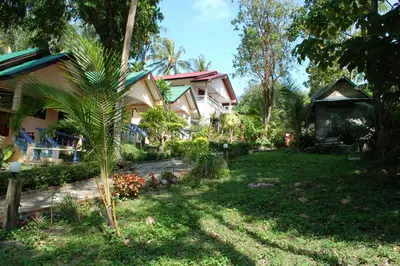 a house with a palm tree in front of a yard at Anawin Bungalows in Ao Nang Beach
