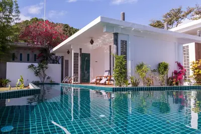 a villa with a swimming pool in front of a house at Yao Yai Beach Resort in Ko Yao Yai