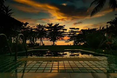 a view of a sunset from a pool with the ocean at Yao Yai Beach Resort in Ko Yao Yai