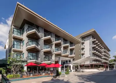 a large building with red umbrellas in front of it at Luxury Beach Apartments by MVP in Patong Beach