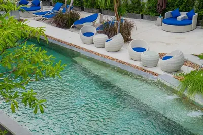 a pool with blue chairs and a swimming pool at The Woods Natural Park Resort Phuket in Kamala Beach
