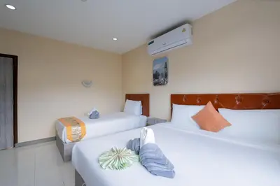 a hotel room with two beds and a window at Square One Hotel Patong in Patong Beach