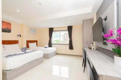a hotel room with two beds and a window at Square One Hotel Patong in Patong Beach