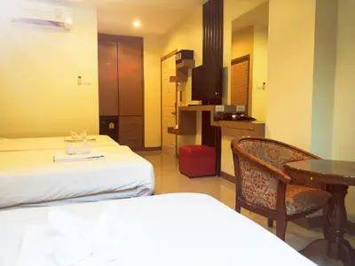 a hotel room with two beds and a table and chair at Pimrada Hotel in Patong Beach