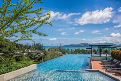 a swimming pool with chairs and a view of the water at 6-Ave Surin Apartment in Surin Beach