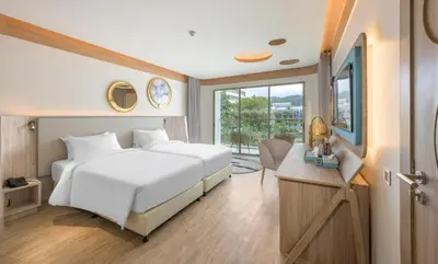 a bedroom with a large white bed and a desk at Andaman Embrace Patong, Phuket in Patong Beach
