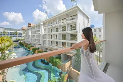 a woman standing on a balcony looking out at a building at Andaman Embrace Patong, Phuket in Patong Beach