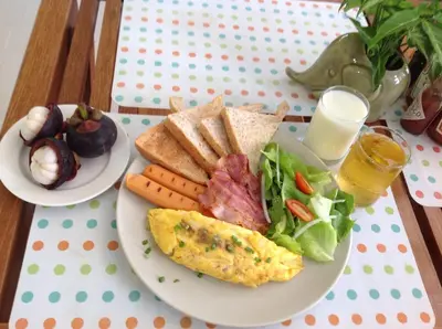 a plate of food with an omelet and a salad at Sandy House Rawai in Rawai Beach