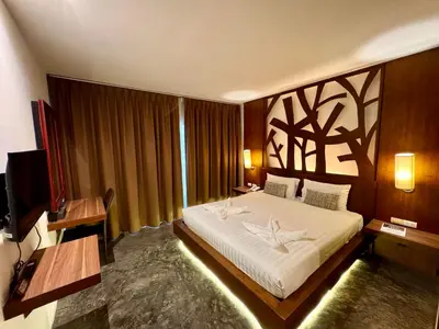 a bedroom with a large bed and a television at De Cozé Hotel in Patong Beach
