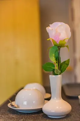 a white rose in a white vase on a table at Pro Andaman Place in Karon Beach