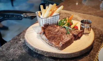 a plate of steak and french fries on a table at Aurico Kata Resort & Spa - SHA Extra Plus in Kata Beach