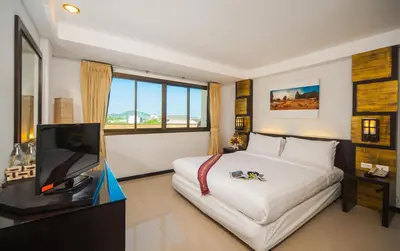 a hotel room with a bed and a tv at Crystal Inn in Phuket Town
