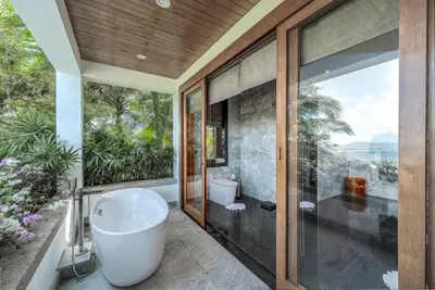 a bathroom with a bath tub and a window at Baan Phu Prana Boutique Villa in Surin Beach