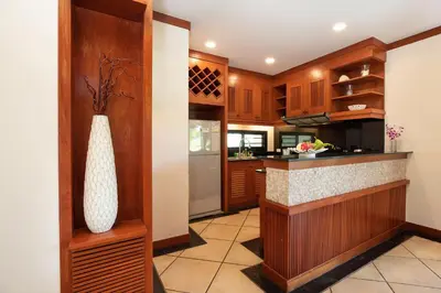 a kitchen with wooden cabinets and a vase at Tropical Living at 3BR Pool Villa Bianca, Baan Bua Luxury Estate, Nai Harn Beach in Rawai Beach