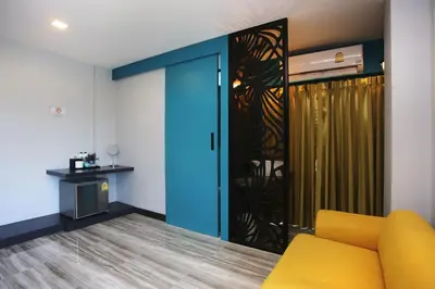 a living room with a yellow couch and a sliding door at Nam Naka Boutique Hotel - SHA Plus in Phuket Town