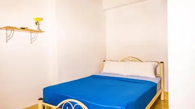 a small room with a bed with a blue blanket at Sabina Guesthouse Kamala in Kamala Beach