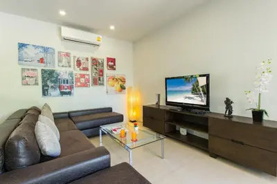 a living room with a couch and a flat screen tv at West facing 3br Boutique Pool Villa by Intira Villas in Rawai Beach