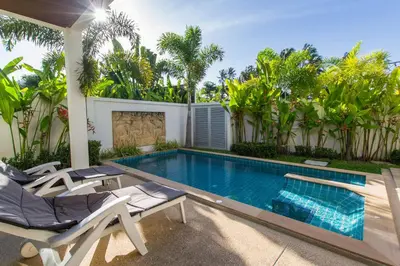 a swimming pool with chaise lounge chairs next to a house at West facing 3br Boutique Pool Villa by Intira Villas in Rawai Beach