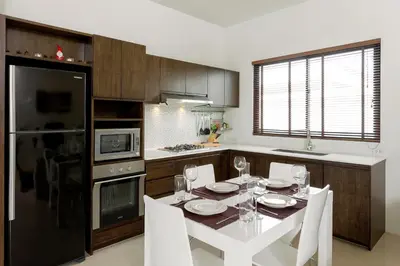 a kitchen with a white table and white chairs and a kitchen with at Big Buddha View 3br Pool Villa by Intira Villas in Rawai Beach