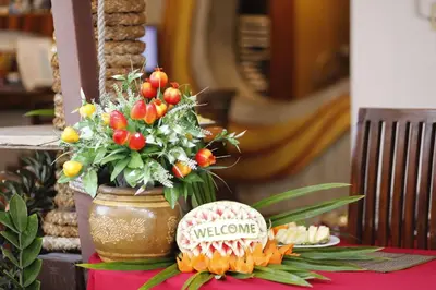 a table topped with a vase with flowers and a baseball at Baan Kamala Fantasea Hotel in Kamala Beach